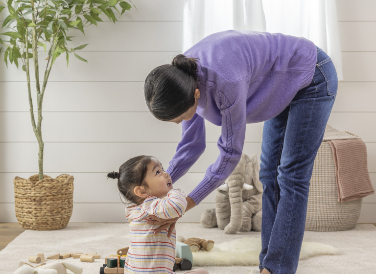 A woman bending to pick up a little girl